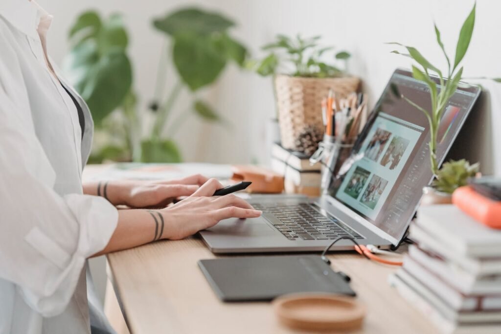 Woman working retouching photo on laptop at convenient workplace, mobile app design and development